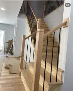 View of a wooden staircase with black metal balusters and a top railing.