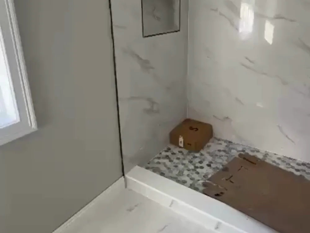 Bathroom tile installation showing walk-in shower walls and mosaic shower floor