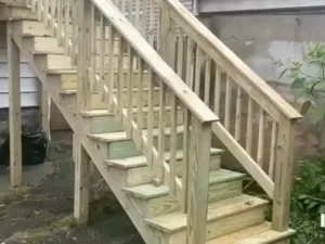 Exterior wooden staircase construction with pressure-treated lumber and safety railings for residential access