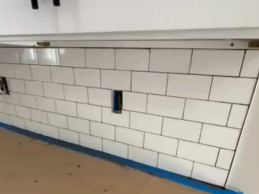Subway tile backsplash installation with aligned tiles and outlet cutout