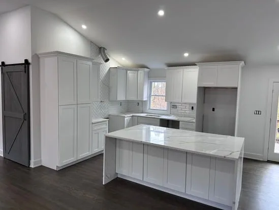 White kitchen cabinets and a sliding gray barn door featured in an open concept renovation Shelton.