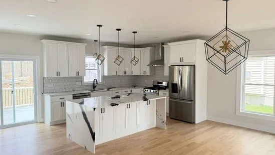 A new build kitchen design featuring white cabinetry and a large black and white marble waterfall island.